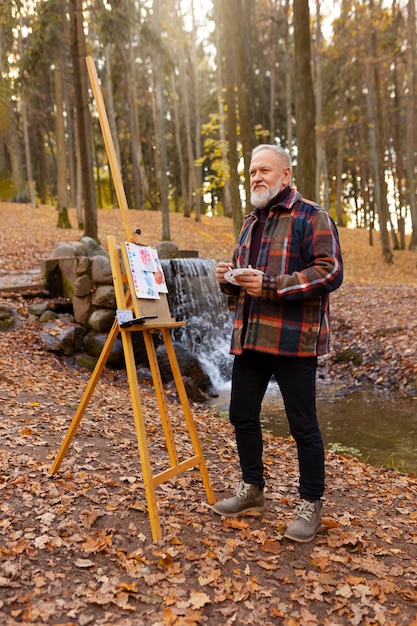 Aquarelkunstenaar buiten in het bos met ezel en canvas