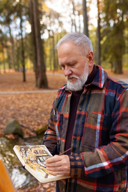 Gratis foto aquarelkunstenaar buiten in het bos