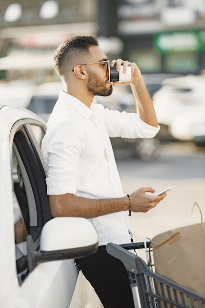 Arabische man gebruikt smartphone terwijl hij wacht op het opladen van de batterij in de auto.