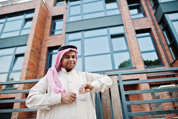 Arabische man uit het Midden-Oosten poseerde op straat tegen modern gebouw en keek naar zijn gouden horloges