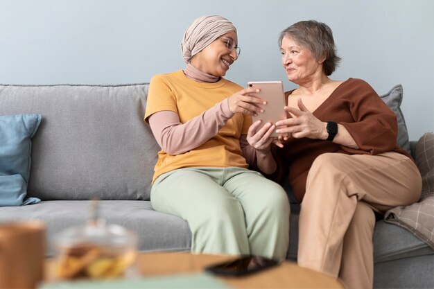 Arabische vrouw leert senior vrouw tablet te gebruiken in de woonkamer