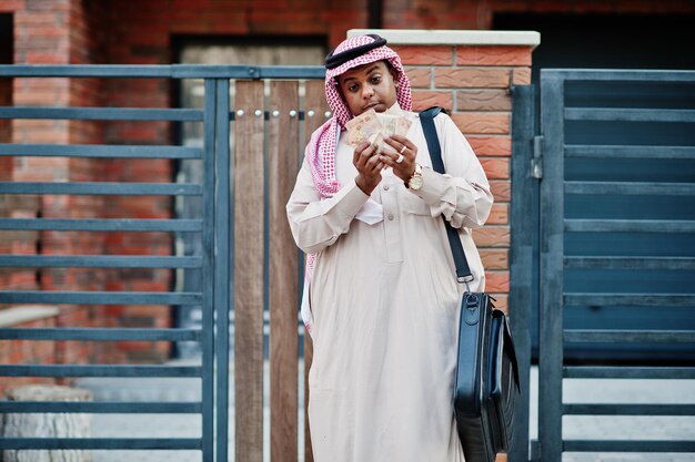 Arabische zakenman uit het Midden-Oosten poseerde op straat tegen modern gebouw met zwarte handtas en eurogeld