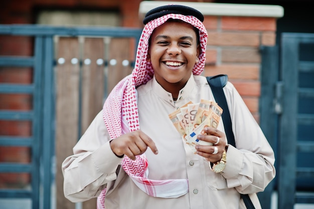 Arabische zakenman uit het midden-oosten poseerde op straat tegen modern gebouw met zwarte handtas en eurogeld
