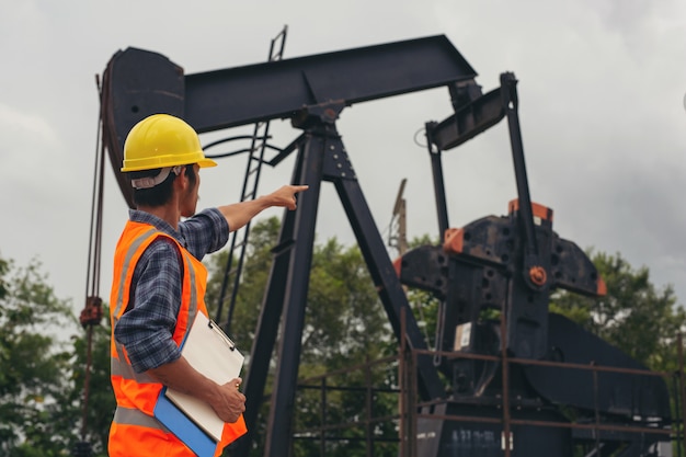 Gratis foto arbeiders die en zich naast werkende oliepompen bevinden controleren.