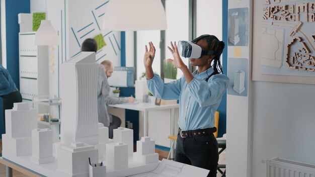 Architect die een vr-bril gebruikt om het gebouwmodel en de constructielay-out te ontwerpen. Vrouwelijke aannemer die met virtual reality-headset werkt om de vastgoedstructuur te plannen en een stedelijk project te creëren.