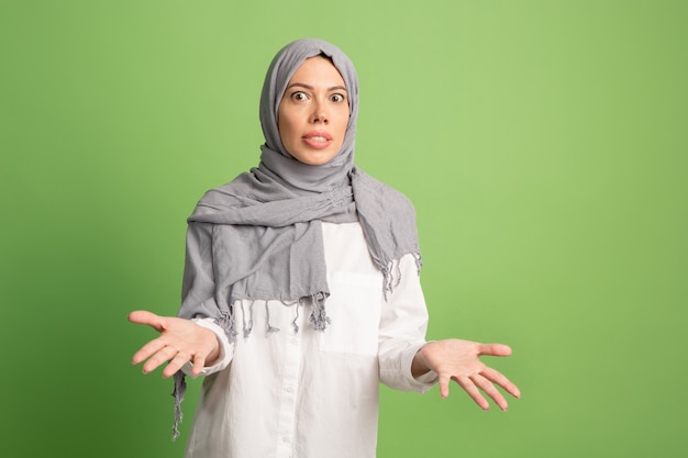 Argumenteren, argumenteren concept. Arabische vrouw in hijab. Portret dat van meisje, bij groene studioachtergrond stelt. Jonge emotionele vrouw. De menselijke emoties, gezichtsuitdrukking concept. Vooraanzicht.