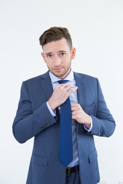 Arrogante knappe jonge zakenman aanpassende stropdas