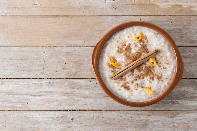 Arroz con leche Rijstebrij met kaneel in kleikom op houten tafel