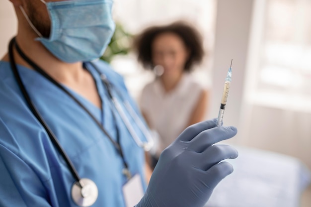 Arts die een spuit met vaccin naast een patiënt houdt