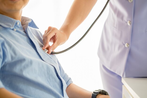 Arts die een stethoscoop gebruikt die patiënt met het onderzoeken controleert
