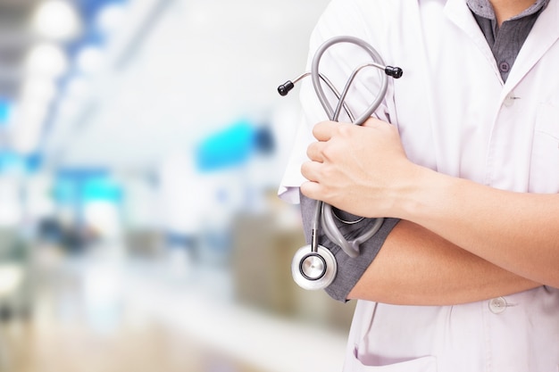 Arts met een stethoscoop in de handen en de ziekenhuisachtergrond