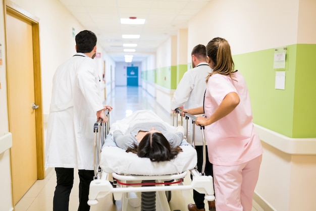 Gratis foto artsen en verpleegsters duwen vrouwelijke patiënt op brancard in gang in ziekenhuis