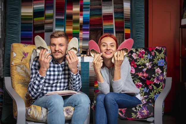 Assortiment. Paar kiezen van textiel thuis decoratie winkel, winkel. Maken van interieurontwerp tijdens quarantaine. Gelukkige man en vrouw, jong gezin zien er dromerig uit, vrolijk materiaal kiezen.