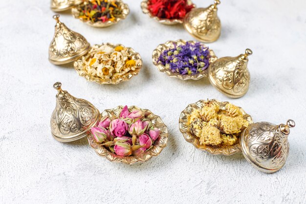Assortiment van droge thee in gouden vintage mini bordjes. Thee soorten achtergrond