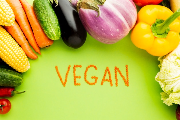 Assortiment van groenten op groene achtergrond met vegan belettering