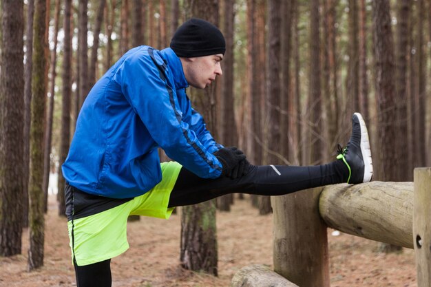 Atleet die zich uitstrekt in het bos