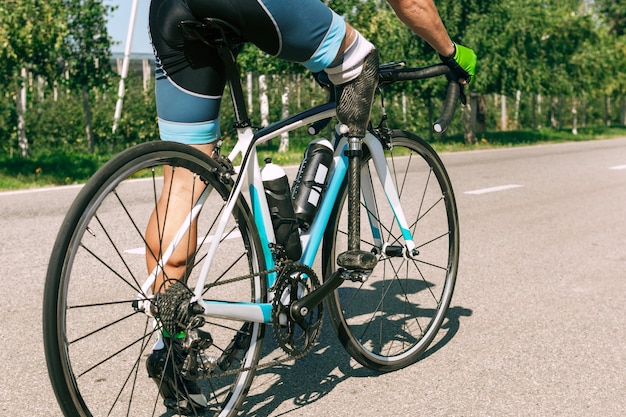 Atleet met een handicap of geamputeerde training in fietsen op zonnige zomerdag. Professionele mannelijke sportman met beenprothese buiten oefenen. Gehandicapte sport en gezonde levensstijl concept.