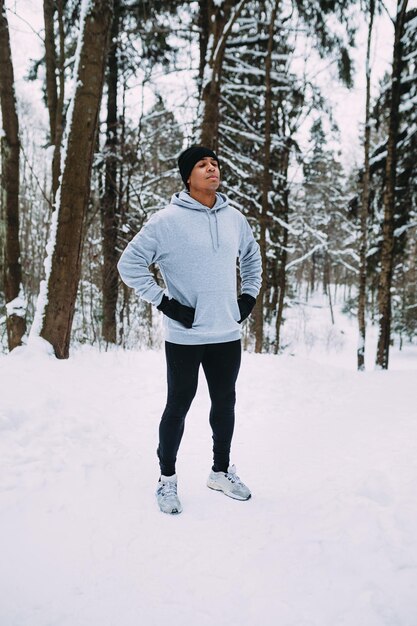 Atleet staande in een bos Man rust na oefeningen