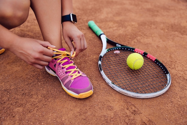 Atletenvrouw die klaar voor het spelen van een spel van tennis, bindende schoenveters wordt.