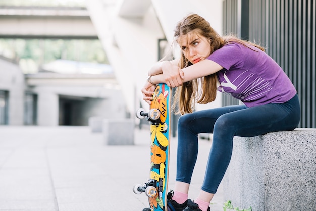 Atletisch meisje leunt op haar kleurrijke skateboard