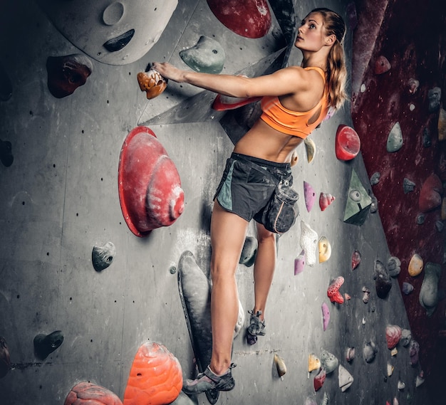 Atletische brunette vrouw op indoor klimmuur.