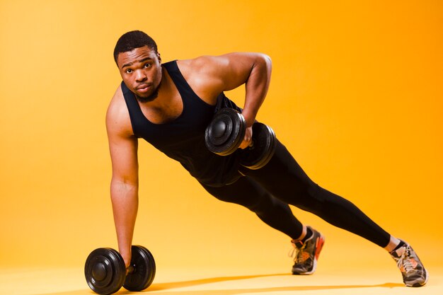 Gratis foto atletische man met gewichten tijdens het sporten