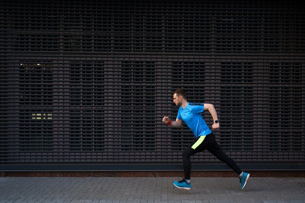 Atletische mens die bij stedelijke straat tegen grijze achtergrond loopt