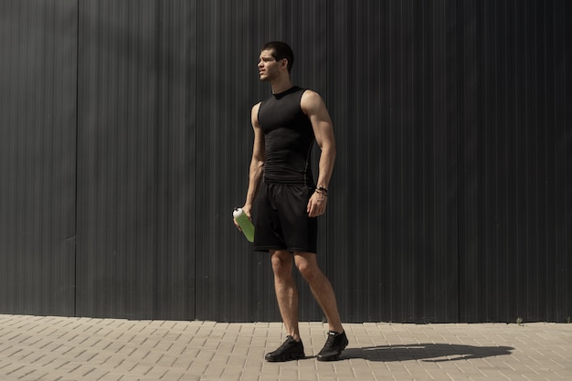 Atletische moderne jonge man die zich voordeed op een grijze metalen muur