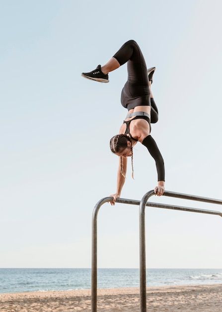 Gratis foto atletische vrouw doet fitnesstraining buiten aan het strand