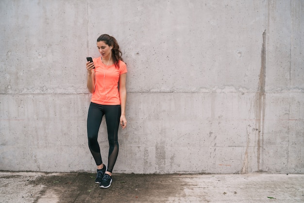 Gratis foto atletische vrouw met behulp van haar telefoon