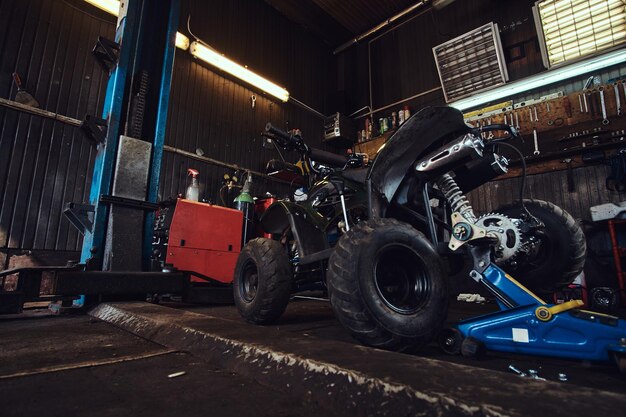 ATV met gebroken wiel bij autoservicewerkplaats wacht om te worden gerepareerd.