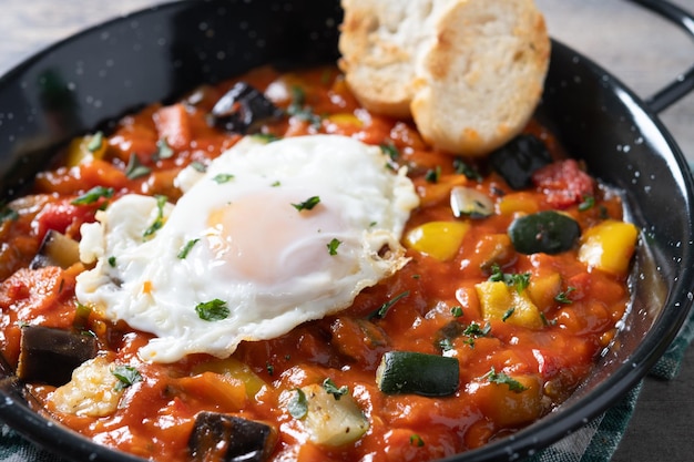 Gratis foto aubergine en eicels paprika's geserveerd in een pan op een houten tafel groente pisto manchego met tomaten courgette