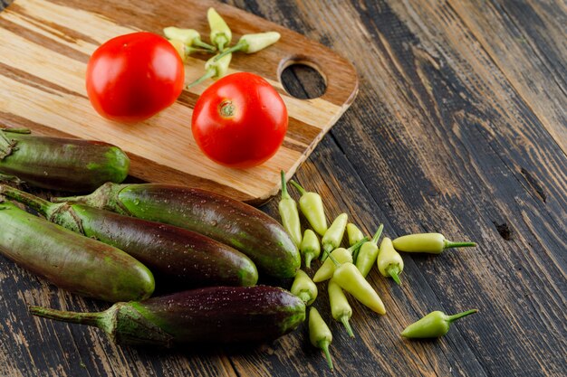 Aubergines met tomaten, paprika's op houten en snijplank, hoge hoek bekeken.