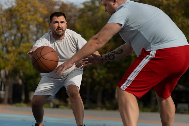 Authentieke scènes van overgrote mannen die basketbal spelen