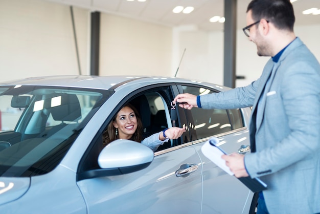 Autodealer die sleutels overhandigt aan de nieuwe auto-eigenaar