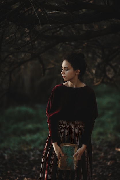 Autumn vibes. Gotische stijl. Donkerbruine vrouw in donkerrode doek