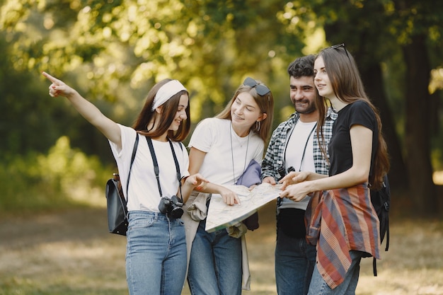 Avontuur, reizen, toerisme, wandeling en mensenconcept. Groep lachende vrienden in een bos. Man met binocularus.