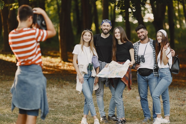 Gratis foto avontuur, wandeling en mensenconcept. groep lachende vrienden in een bos. guy neemt een foto.