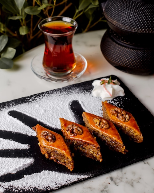 Gratis foto azerbeidzjaanse pakhlava met walnoot geserveerd met zwarte thee in peervormig glas