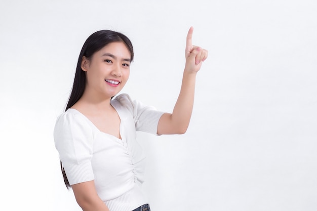 Aziatisch meisje met zwart lang haar draagt een witte overhemdglimlach en wijst met haar hand om iets te presenteren