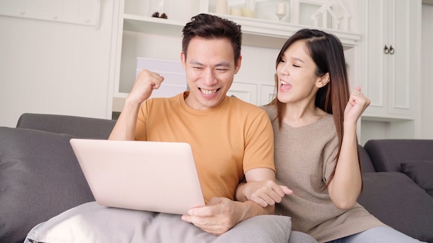 Aziatisch paar dat laptop voor onderzoeksweb in woonkamer thuis met behulp van