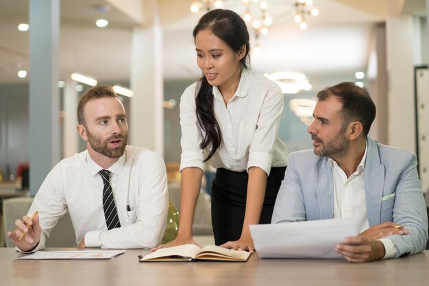 Aziatische bedrijfsvrouw die met collega&#39;s in bureau werkt