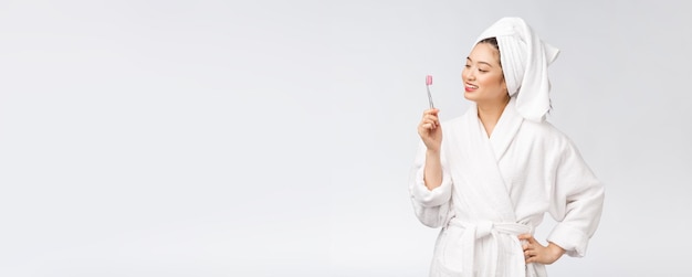 Aziatische gelukkige vrouw met tandenborstel in de stemming van de badjasochtend
