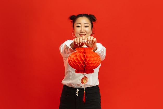 Aziatische jonge vrouw met lantaarn op rode muur
