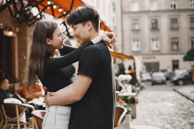 Aziatische jongen en zijn blanke vriendin in vrijetijdskleding staan op de straat van Lviv. Paar knuffelen elkaar terwijl ze samen in de stad wandelen