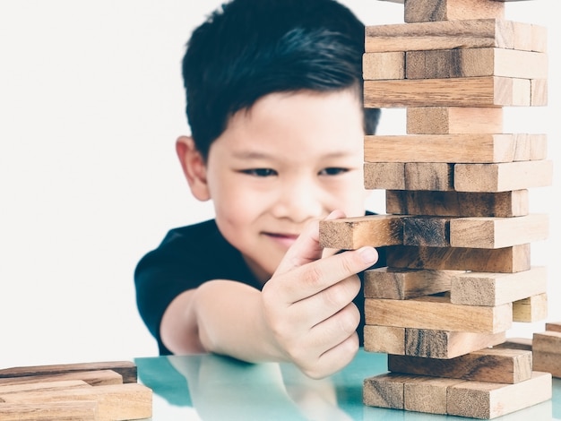 Aziatische jongen speelt houten blokken toren spel voor het beoefenen van fysieke en mentale vaardigheden