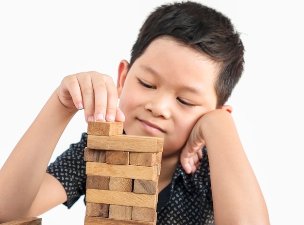 Aziatische jongen speelt Jenga, een houten blokken torenspel