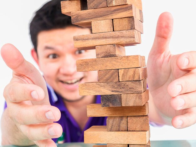 Aziatische kerel speelt Jenga, een houtblokken torenspel