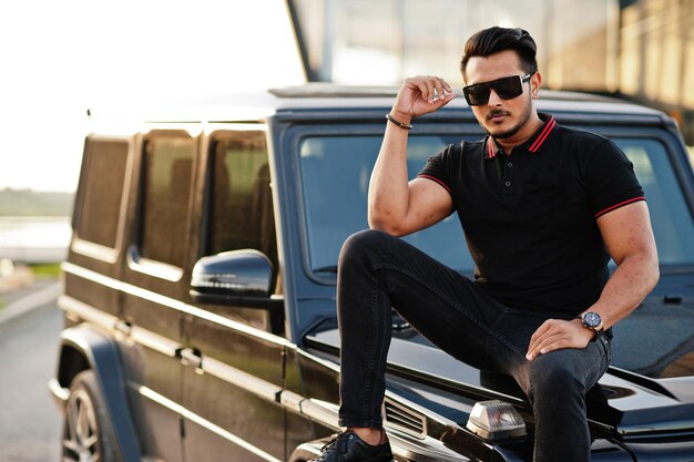 Aziatische man draagt helemaal zwart in de buurt van suv-auto
