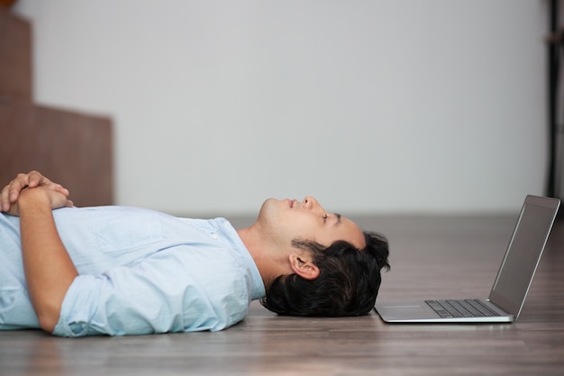 Aziatische man liggend op de vloer op zijn laptop